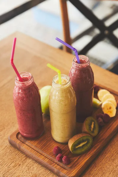 Пляшки з смузі зі свіжих фруктів і ягід на столі — стокове фото