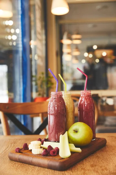 Bottles with fruit smoothies on table in cafe — Stock Photo