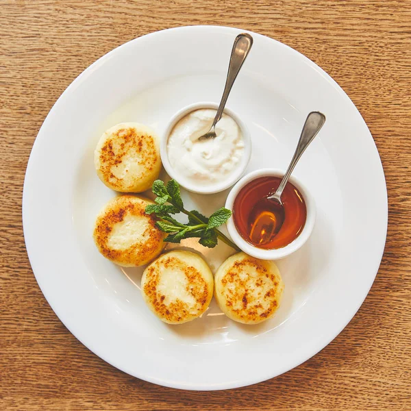 Fried cheese pancakes dish served with honey and sour cream — Stock Photo