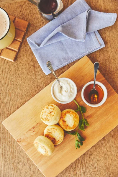 Fried cheese pancakes dish served with honey and sour cream — Stock Photo