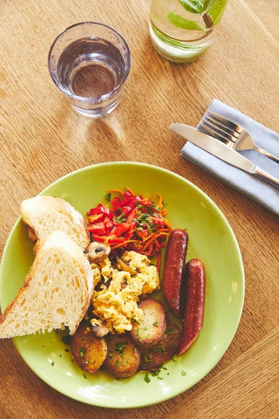 Morning meal with fried eggs served in plate with vegetables and sausage — Stock Photo