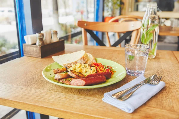 Colazione con uova fritte servita con verdure e salsiccia in piatto — Foto stock