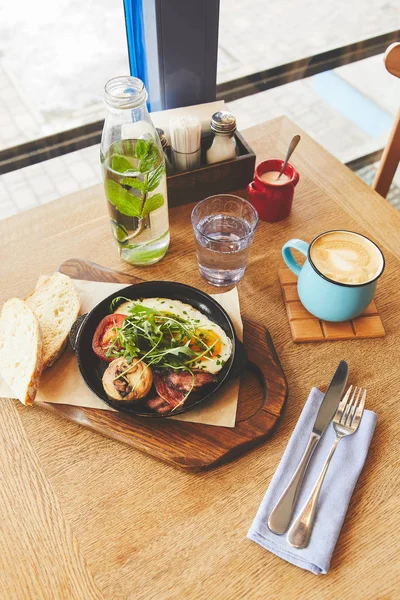 Brunch in restaurant with fried eggs served in pan and coffee — Stock Photo
