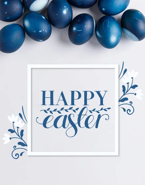 Top view of blue painted easter eggs with happy easter lettering on white — Stock Photo