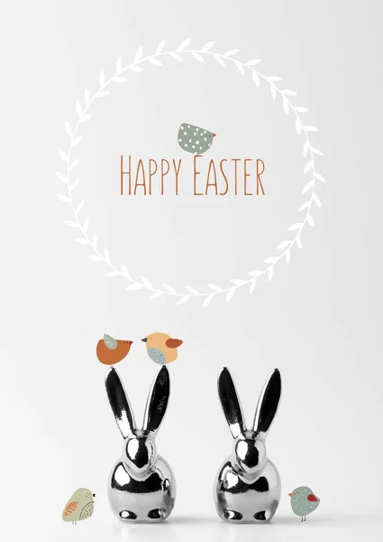 Two statuettes of easter bunnies with drawn birds and happy easter lettering on white — Stock Photo