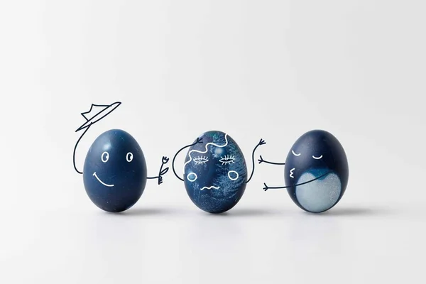 Three blue painted easter eggs with comic drawn faces on white surface — Stock Photo