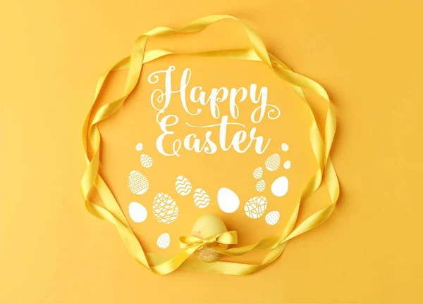 Vista superior de huevo de Pascua pintado de amarillo con cintas en amarillo con letras de Pascua feliz - foto de stock