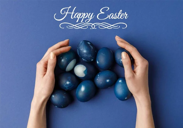 Cropped image of woman touching blue painted easter eggs with happy easter lettering — Stock Photo