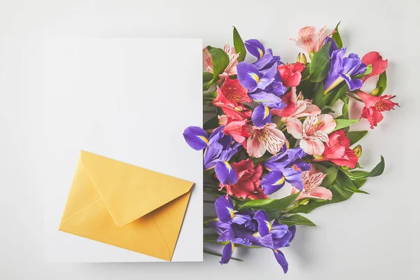 Beautiful floral bouquet, blank card and envelope on grey — Stock Photo