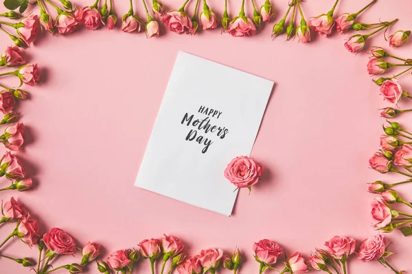 Vue du dessus du cadre fait de belles roses roses et joyeux voeux de la fête des mères sur rose — Photo de stock