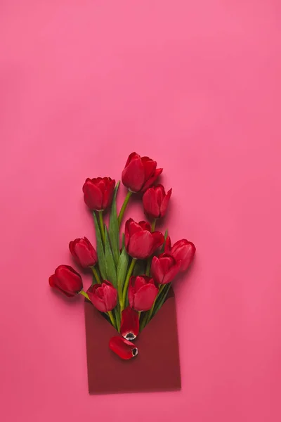 Top view of red tulips in envelope on pink, mothers day concept — Stock Photo