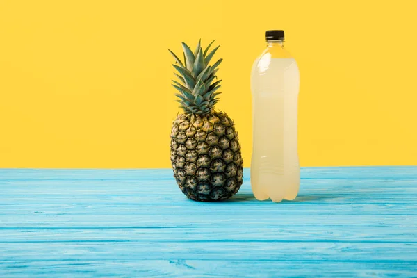 Vue rapprochée du jus frais en bouteille plastique et de l'ananas mûr sur jaune — Photo de stock