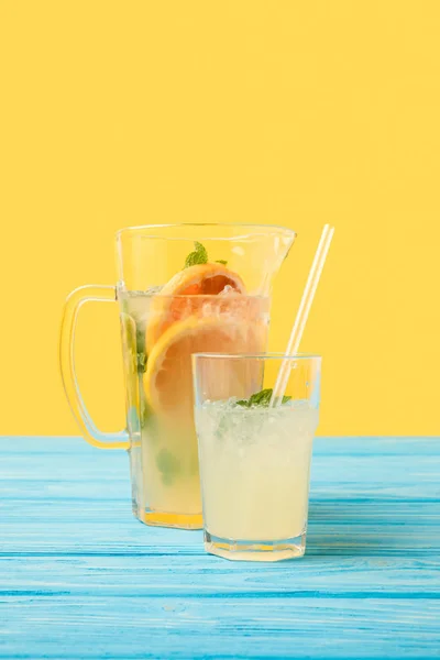 Vue rapprochée de boissons fraîches fraîches fraîches d'été en verre et cruche sur jaune — Stock Photo