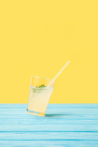 Glass with fresh cold summer cocktail and drinking straw on yellow — Stock Photo