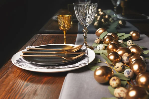 Праздничный стол с пасхальными украшениями и золотыми яйцами — стоковое фото
