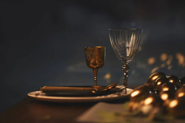 Gläser mit Tellern und goldenen Ostereiern auf dem Tisch — Stockfoto