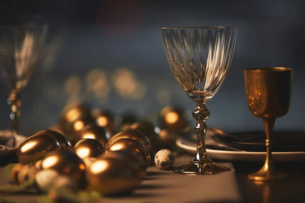 Золоті великодні яйця та келихи на святковому столі — стокове фото