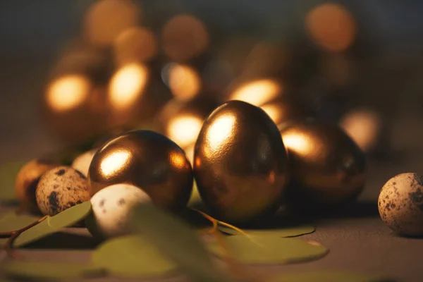 Close up of easter golden eggs with leaves on table — Stock Photo