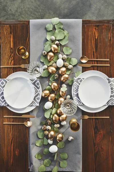 Top view of easter golden eggs, plates and glasses on festive table in restaurant — Stock Photo