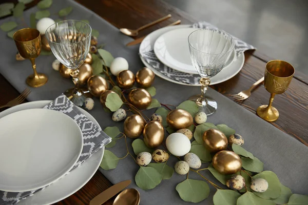 Vista de ángulo alto de huevos de pollo dorado y huevos de codorniz en la mesa de Pascua festiva - foto de stock