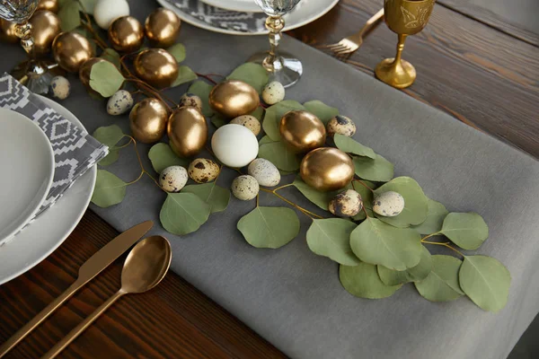 Golden easter eggs on green leaves on festive table — Stock Photo