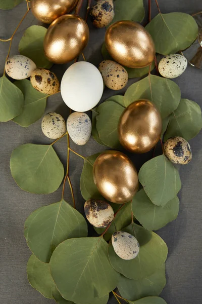Верхний вид золотых пасхальных яиц на зеленых листьях — стоковое фото