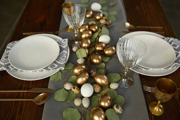 Высокий угол обзора золотых пасхальных яиц на деревянном столе в ресторане — стоковое фото