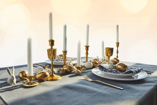 Golden chicken eggs and candles on festive table — Stock Photo