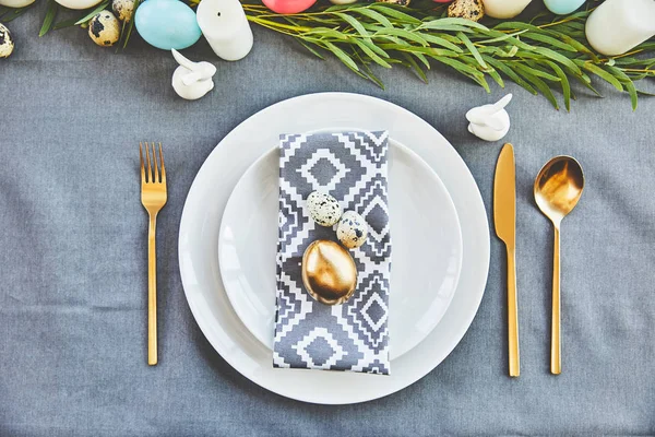 Top view of golden easter egg and quail eggs on festive plates in restaurant — Stock Photo