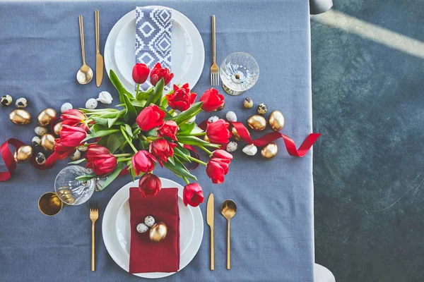 Top view of bouquet of red tulips and easter eggs on festive table — Stock Photo