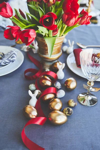 Buquê de tulipas vermelhas e ovos de Páscoa na mesa festiva — Fotografia de Stock