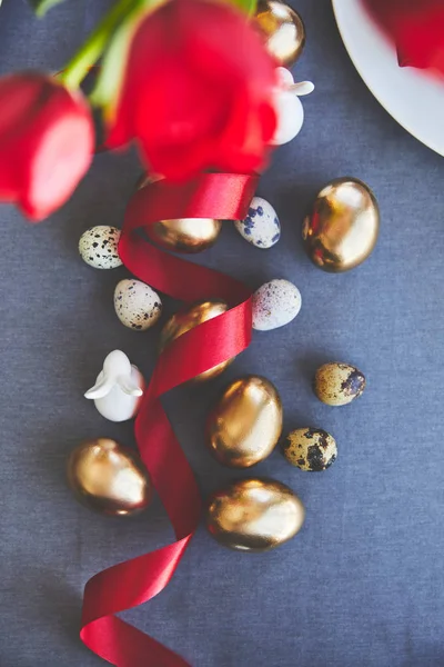 Top view of golden easter eggs and ribbon on tablecloth — Stock Photo