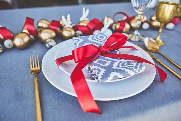 Tavolo decorato con uova d'oro e nastri rossi — Foto stock