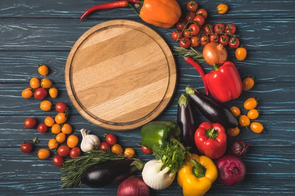 Top view of ripe organic vegetables around wooden board on tabletop — Stock Photo