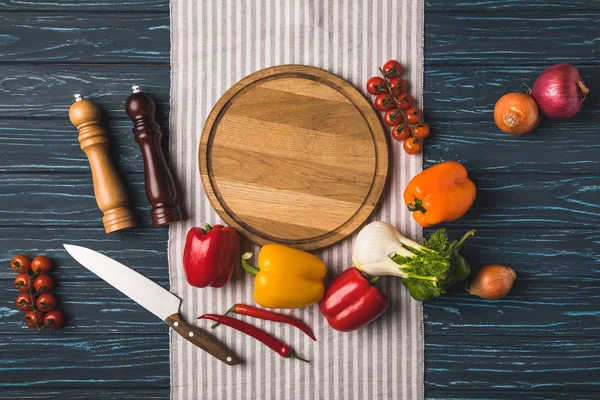 Vista superior de verduras orgánicas maduras y tabla de cortar en mesa de madera - foto de stock