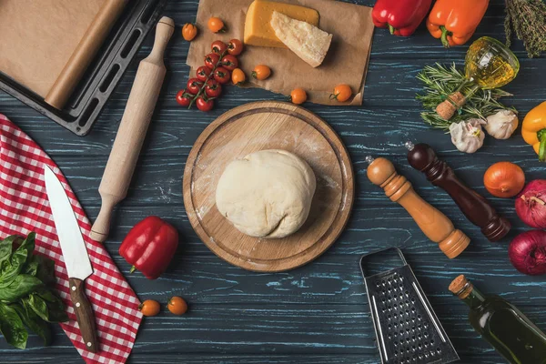 Vue du dessus de la pâte pour pizza sur la planche à découper sur la table — Photo de stock