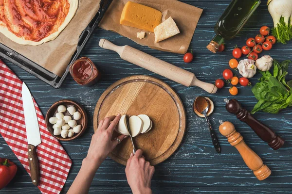 Immagine ritagliata di donna che taglia mozzarella per pizza — Foto stock