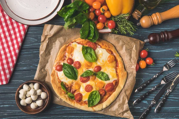 Vista dall'alto di deliziosa gustosa pizza con pomodorini ciliegini e basilico sul tavolo — Foto stock