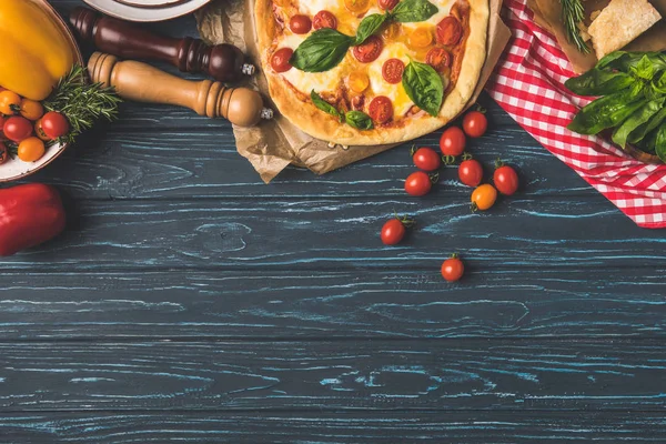 Draufsicht auf appetitlich leckere Pizza und verstreute Kirschtomaten auf dem Tisch — Stockfoto