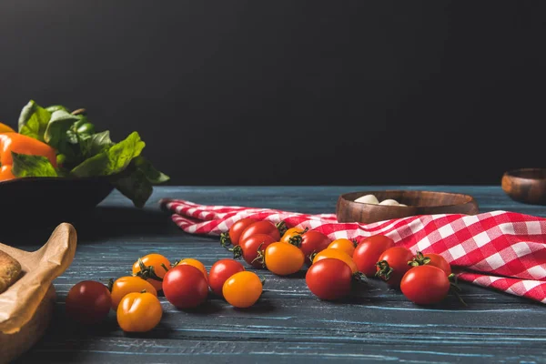 Вишневі помідори та скатертина на дерев'яному столі — стокове фото