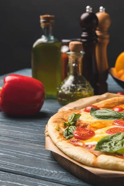 Close up of appetizing tasty pizza with cherry tomatoes and basil on table — Stock Photo