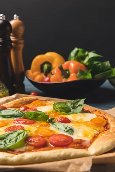 Gros plan d'une délicieuse pizza appétissante avec tomates cerises et basilic — Photo de stock