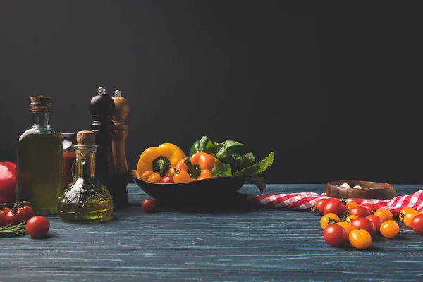 Verduras y aceites sobre mesa de madera en cocina aislada sobre negro - foto de stock