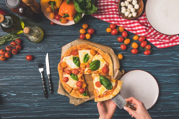 Abgeschnittenes Bild einer Frau, die ein Stück hausgemachte Pizza nimmt — Stockfoto