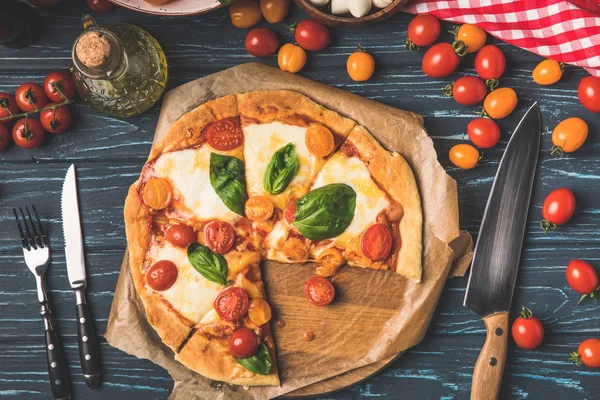 Vue de dessus de la pizza appétissante savoureuse et tomates cerises sur la table — Photo de stock