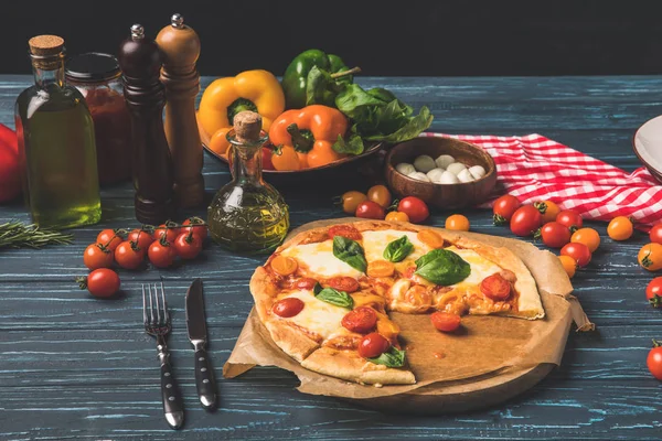 Apetitosa pizza sabrosa en la tabla de cortar en la mesa — Stock Photo