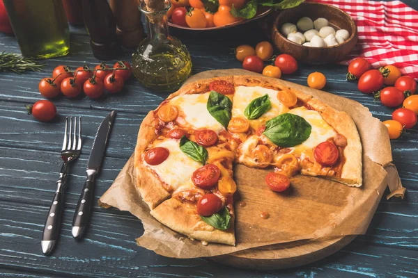 Appétissante pizza savoureuse sur la planche à découper sur la table — Photo de stock