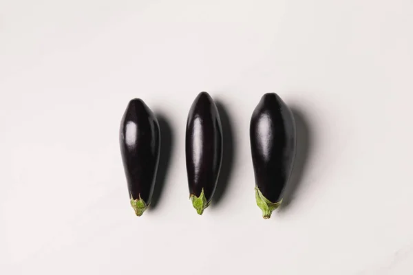 Top view of three eggplants on white surface — Stock Photo