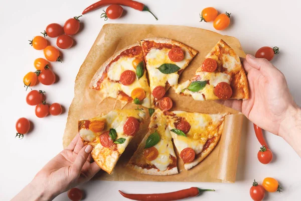 Abgeschnittenes Bild von Frau und Mann, die hausgemachte Pizza auf Weiß nehmen — Stockfoto