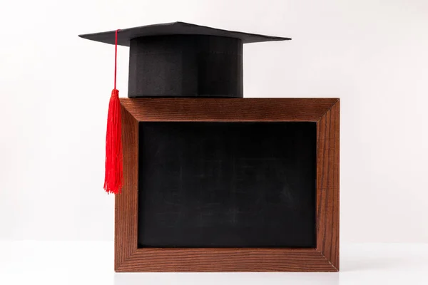 Academic cup on empty blackboard isolated on white — Stock Photo